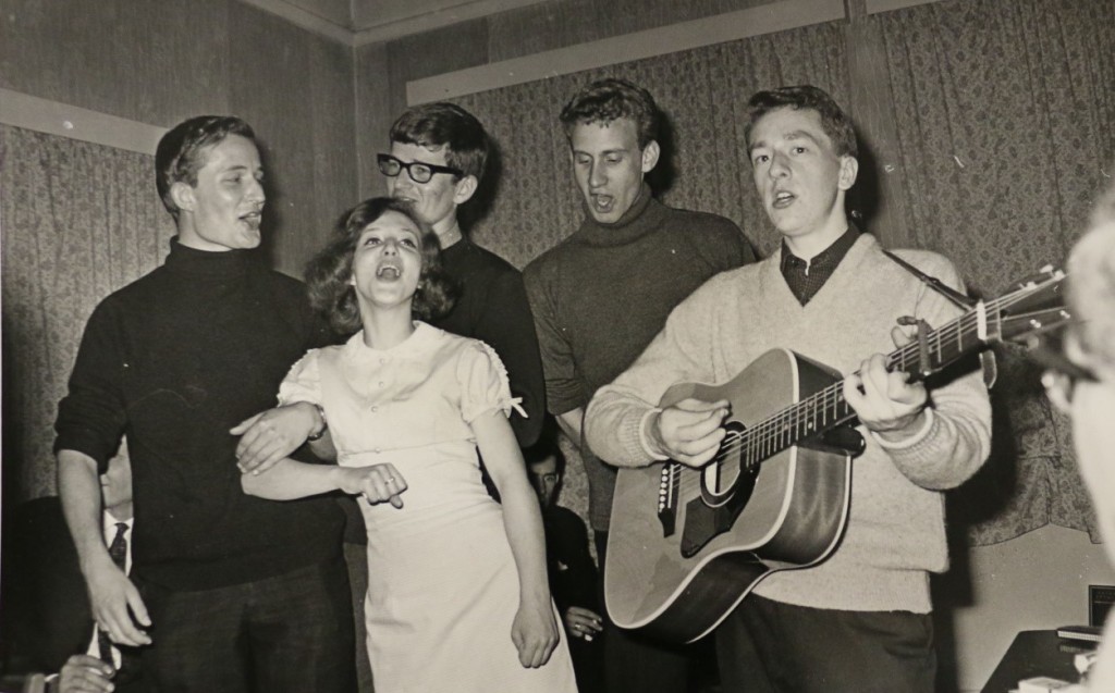 Five members of the Keyroes Folk Group sing around a guitar